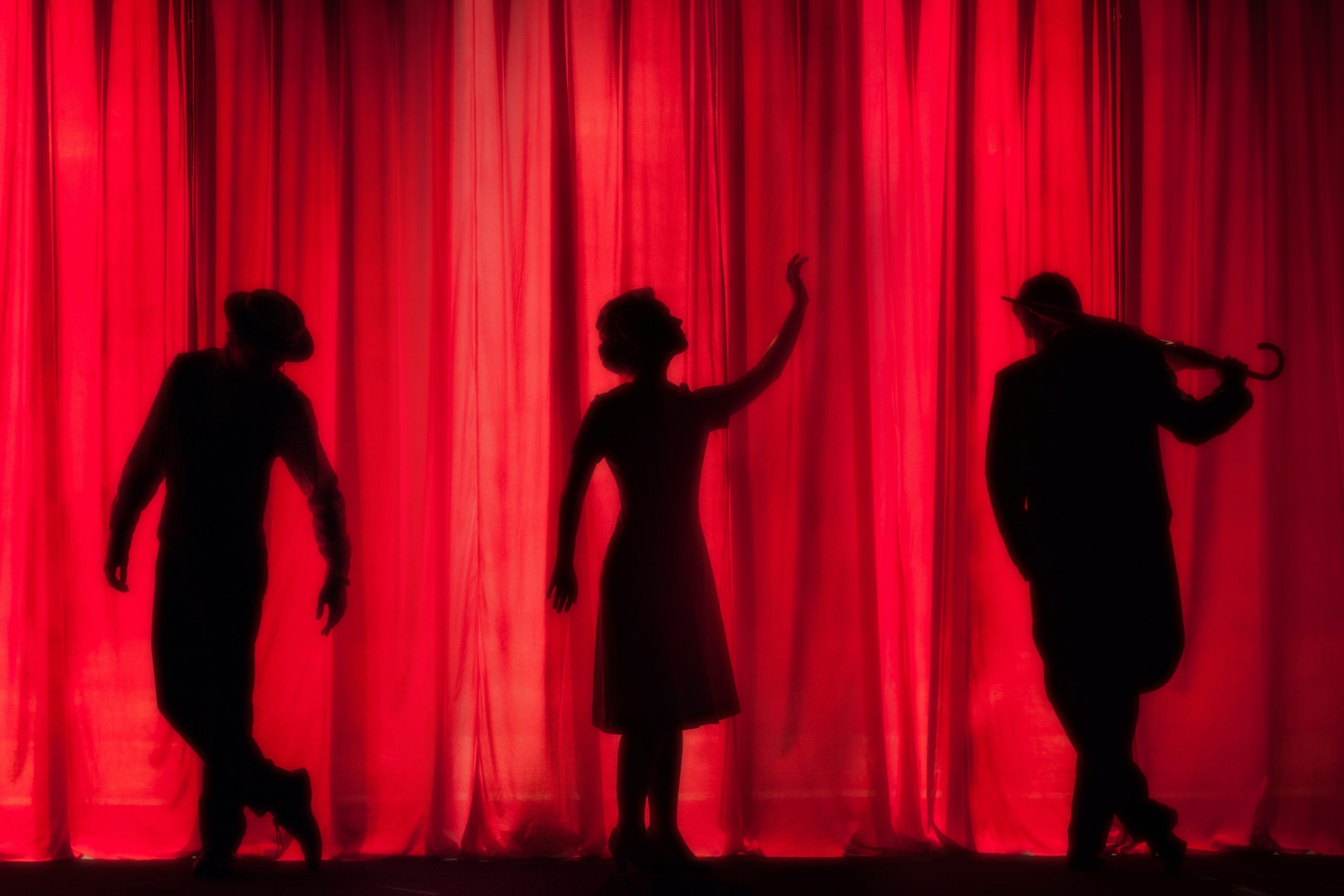 Silhouette of Three Actors in Front of a Red Curtain. One of the many Whitney Attractions
